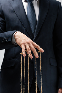 partial view of puppeteer in suit with strings on fingers