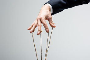 cropped view of puppeteer with strings on fingers isolated on grey
