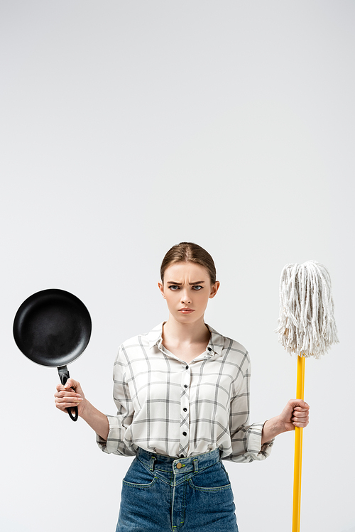 attractive girl posing like puppet with mop and frying pan isolated on grey