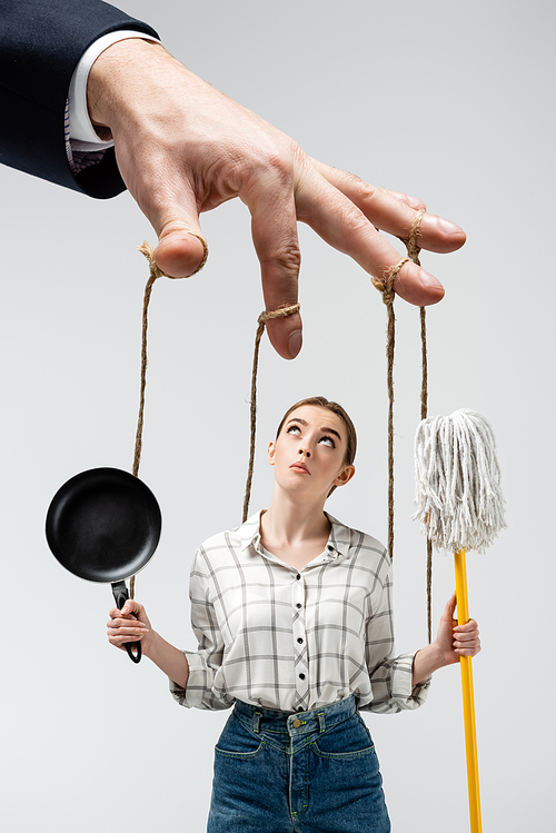 cropped view of puppeteer manipulating girl with mop and frying pan isolated on grey