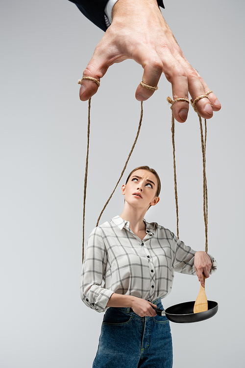 cropped view of puppeteer manipulating girl with frying pan isolated on grey