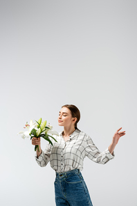 pleased attractive girl posing like puppet with flowers isolated on grey