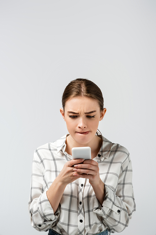concentrated attractive girl using smartphone isolated on grey