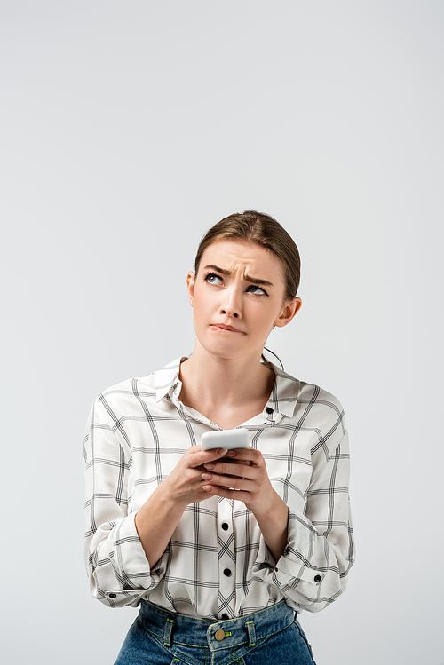 pensive attractive girl using smartphone isolated on grey