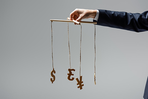 cropped view of businessman holding currency signs on strings isolated on grey