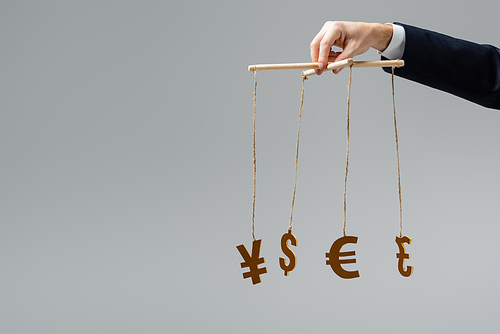 cropped view of businessman holding currency signs on strings isolated on grey