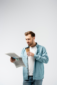 young man reading newspaper and drinking coffee isolated on grey