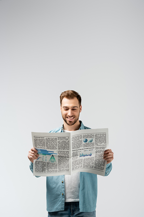 smiling young man reading newspaper isolated on grey