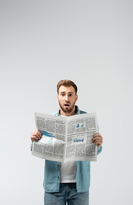 shocked young man with newspaper isolated on grey