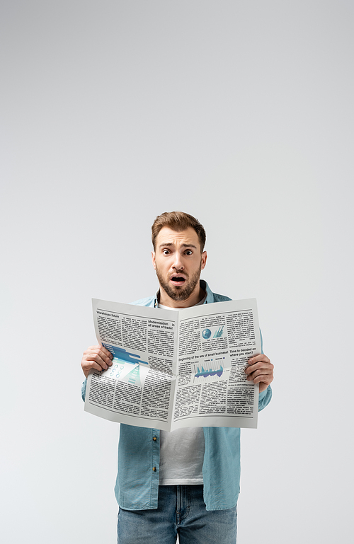 shocked young man with newspaper isolated on grey