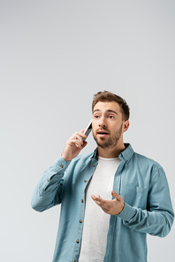 excited young man talking on smartphone isolated on grey