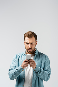 confused young man using smartphone isolated on grey