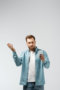 confused young man using smartphone isolated on grey