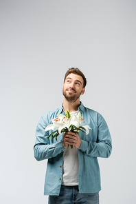 dreamy young man with floral bouquet isolated on grey