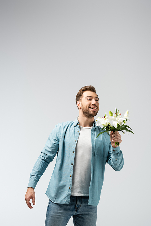 happy young man with floral bouquet isolated on grey