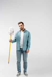 sad young man with mop isolated on grey
