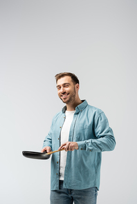 smiling young man with frying pan and spatula isolated on grey