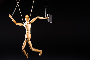 wooden marionette on strings with suitcase isolated on black