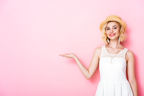 woman in straw hat pointing with hand on pink