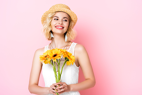 woman in straw hat and white dress holding flowers on pink