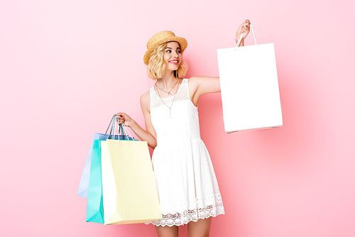 young woman in white dress holding shopping bags on pink
