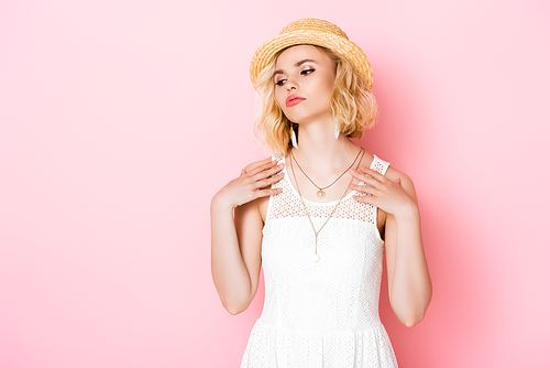 tired young woman in straw hat and white dress on pink