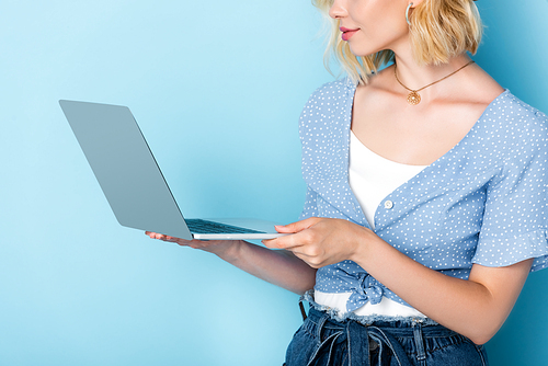 cropped view of young woman using laptop on blue