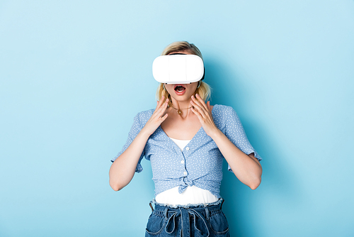 young and shocked woman in virtual reality headset on blue