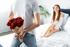 cropped view of man with bouquet and box and smiling woman looking at him