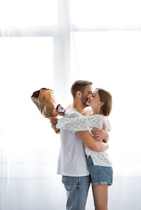 side view of smiling woman with engagement ring and bouquet hugging man