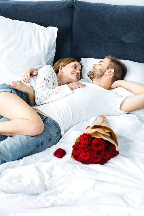 smiling and attractive woman and handsome man hugging in bed