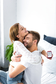 handsome man hugging smiling woman with engagement ring
