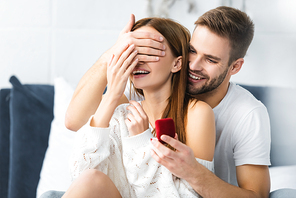 smiling man doing marriage proposal and obscuring face of woman