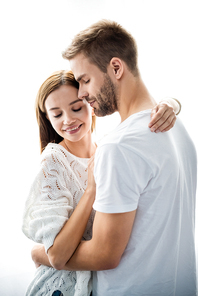 handsome man hugging attractive and smiling woman in apartment