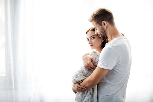 handsome man hugging attractive woman in apartment