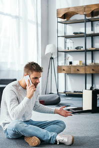 handsome man talking on smartphone in robbed apartment
