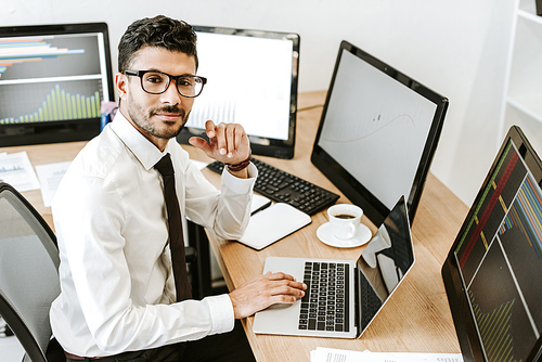 high angle view of smiling bi-racial trader sitting near computers and 