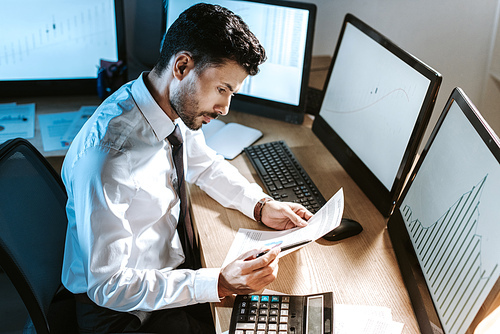 high angle view of bi-racial trader looking at paper