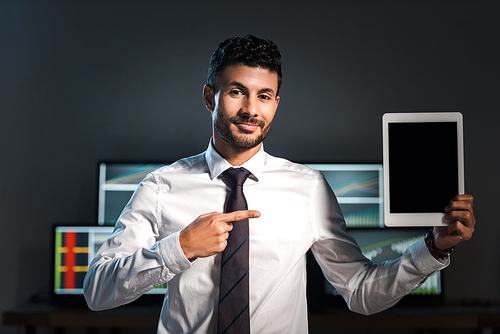 smiling bi-racial trader pointing with finger at digital tablet