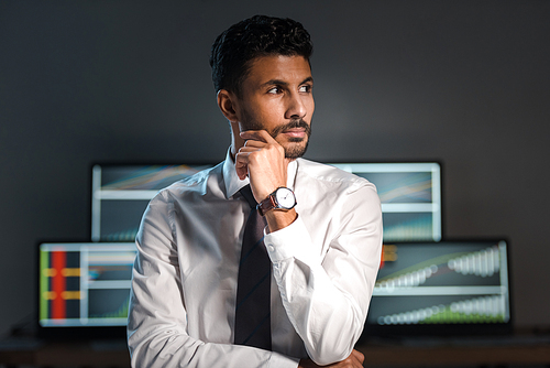 pensive and handsome bi-racial trader looking away in office