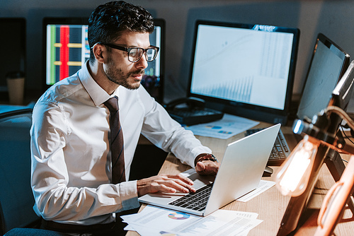 bi-racial trader using laptop and sitting at table in office