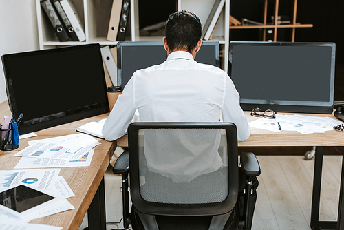 back view of bi-racial trader sitting at table in office