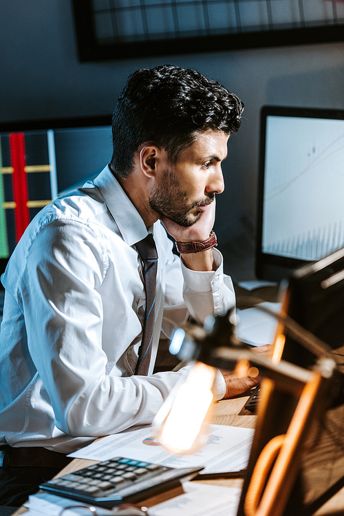 side view of bi-racial trader sitting at table and looking away