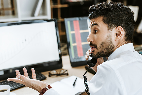 side view of bi-racial trader talking on telephone in office