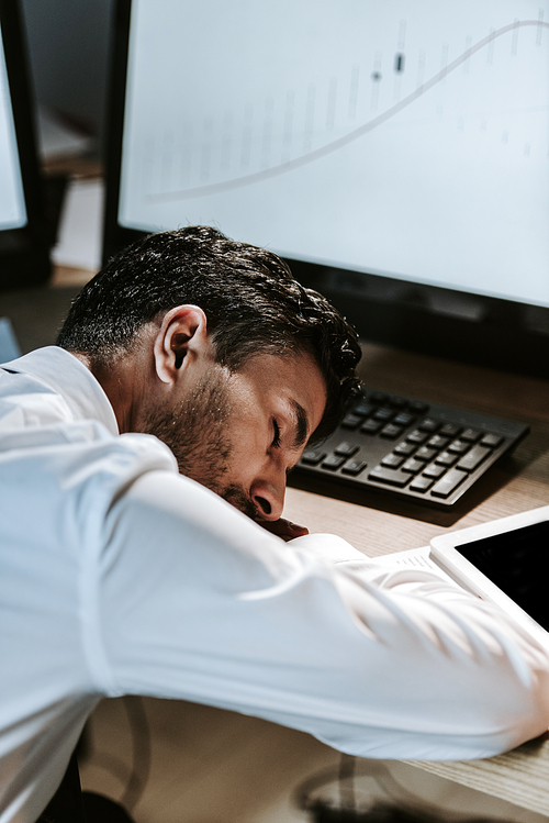 high angle view of handsome bi-racial trader sleeping on wooden table in office