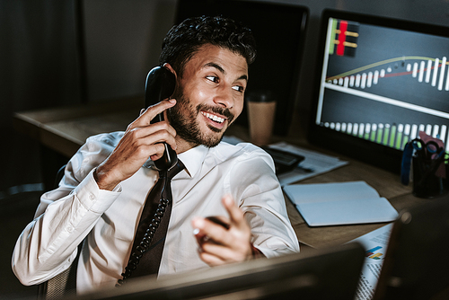 smiling bi-racial trader talking on telephone and looking away