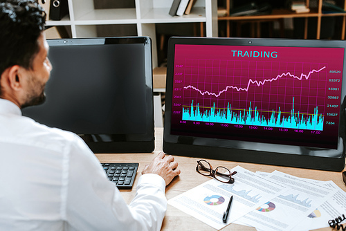 cropped view of bi-racial trader using computer with lettering trading