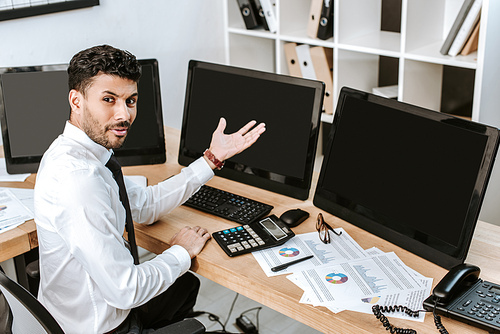 angry bi-racial trader pointing with hand at computer with copy space