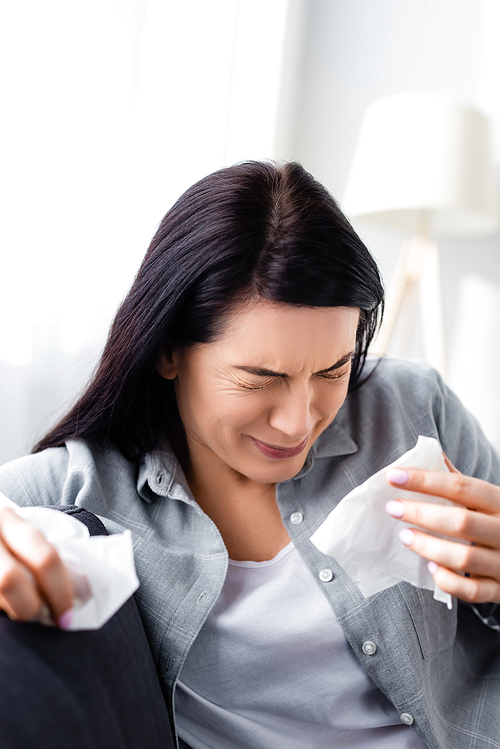 selective focus of allergic woman sneezing and holding tissues