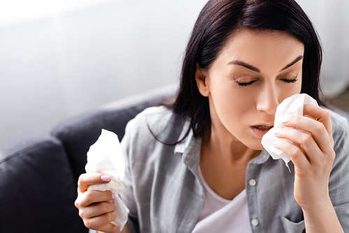 allergic woman with closed eyes holding tissues